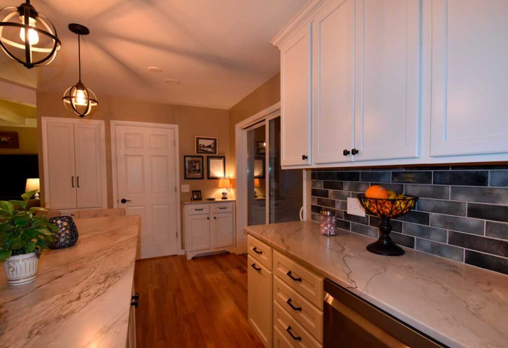 Final remodeled kitchen with wood floors, white cabinets and marble countertops